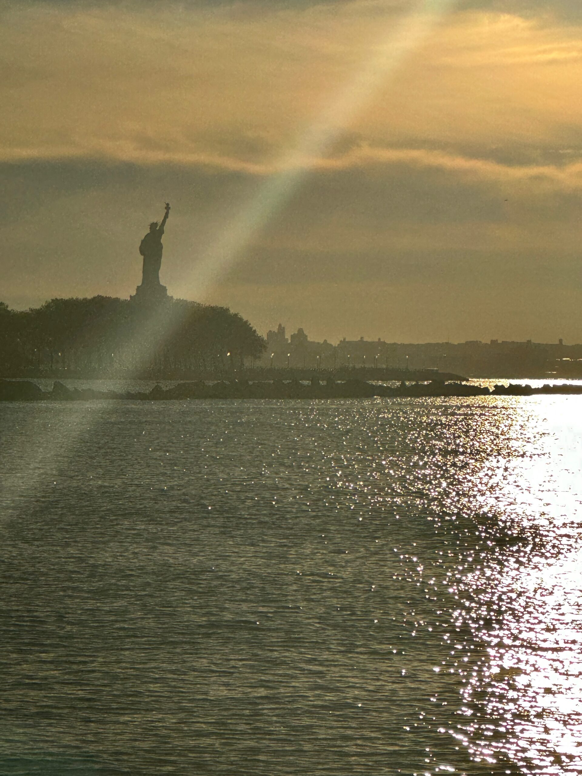 The Statue of Liberty across sparkling harbor water